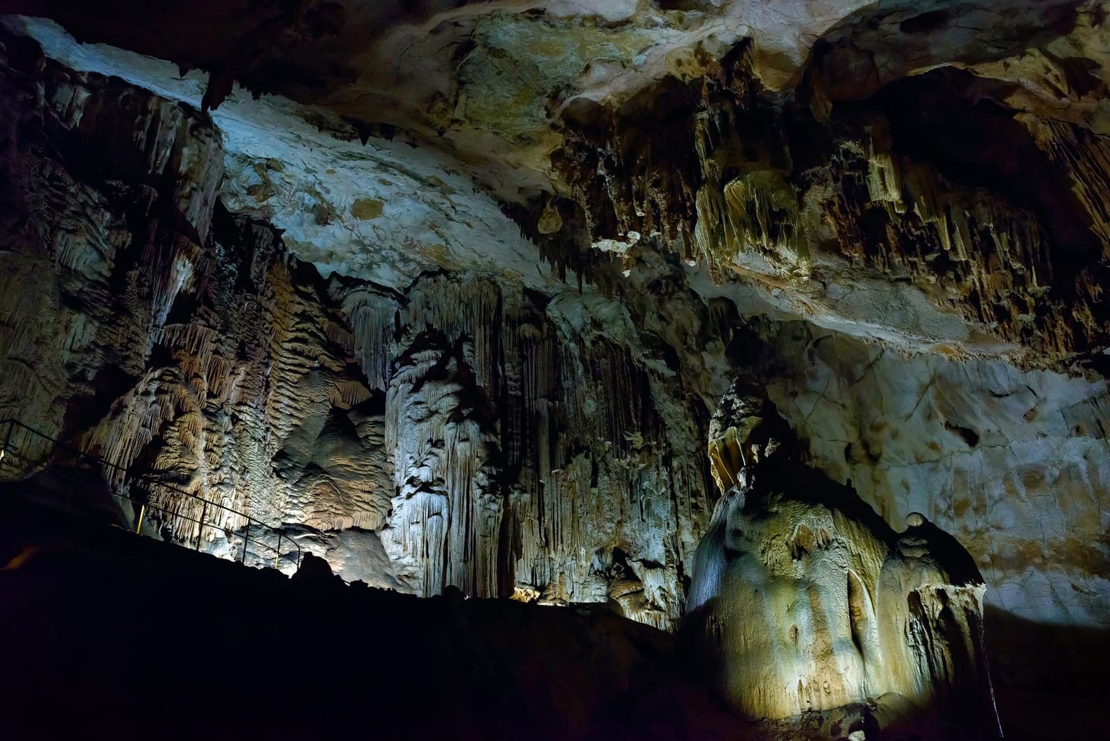 Câmara de caverna com formações de flowstone e corrimão de visitação, exemplo ilustrativo.