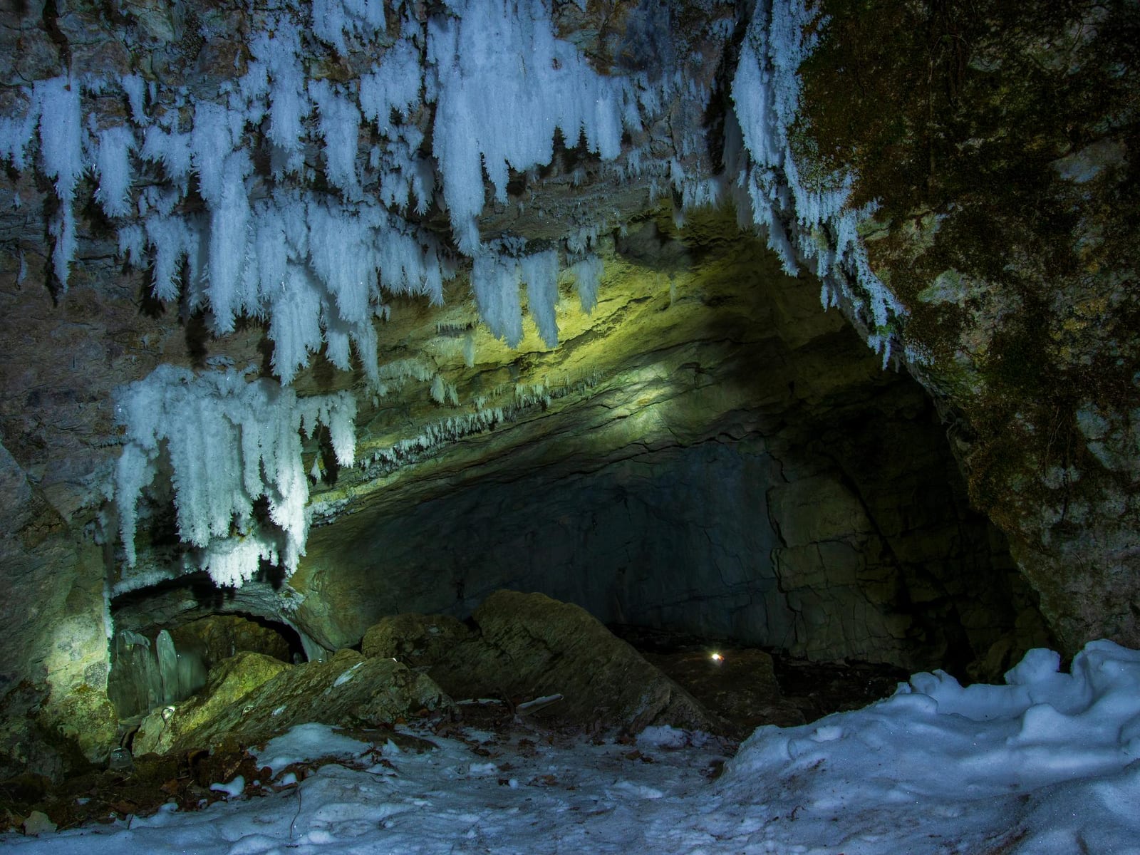 Entrada de caverna coberta de neve com formações de gelo, Serra da Espeleologia.